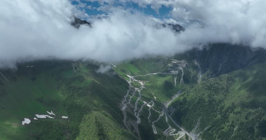Aerial footage of winding road on beautiful high altitude grassland and snow capped mountain landscape