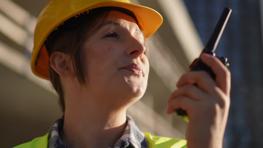 A construction worker in safety gear using a walkie-talkie on site, ensuring effective communication.