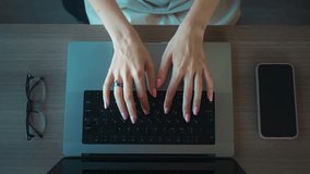 Womans hands typing on laptop keyboard on wooden desk, with smartphone and eyeglasses next to it, suggesting a modern work from home setup. Woman typing on laptop in home office, digital workflow. - Powered by Shutterstock - Get 15% off with code: PIKWIZARD15