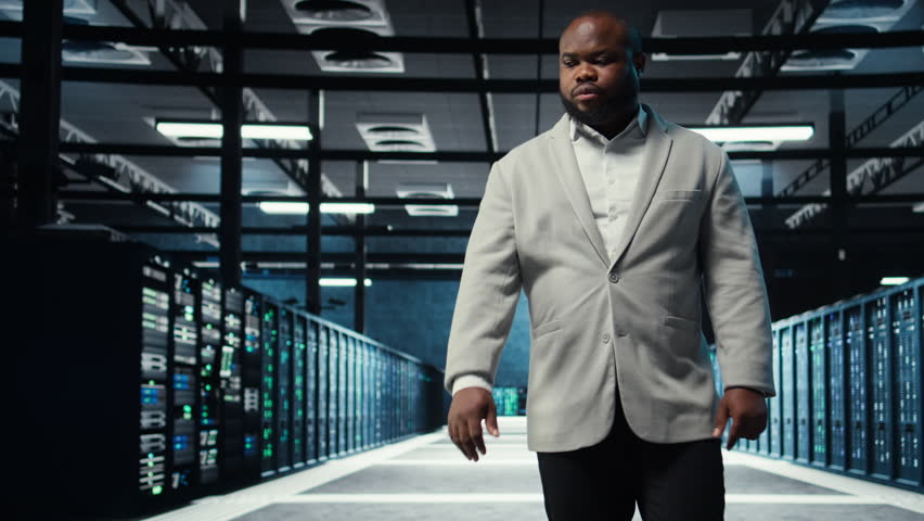 Admin working in high tech server hub capable of processing and storing vast amounts of data. African american IT specialist troubleshooting server rows controlling network resources, camera A - Powered by Shutterstock - Get 15% off with code: PIKWIZARD15