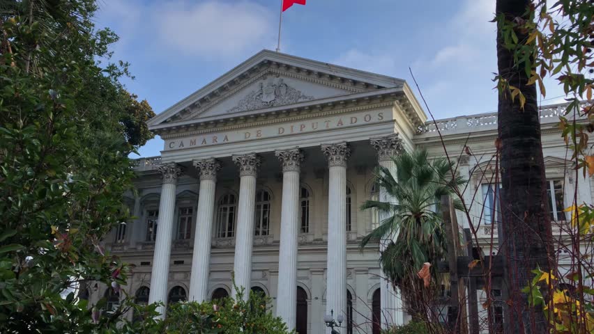 Exterior view of a government building used by the Chilean Chamber of Deputies in Santiago, Chile. The modernist architecture contrasts with nearby historical structures.