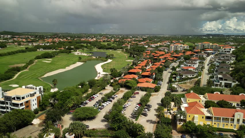 Sunny drone view of Blue Bay golf course with green fairways, palm trees, and villas—no sea visible. Perfect for luxury travel, sports promos, or lifestyle branding.