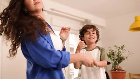 Real time zoom in side view of crop anonymous mother with long hair and son looking away while standing on sofa and holding hands of jumping boy in daylight - Powered by Shutterstock - Get 15% off with code: PIKWIZARD15