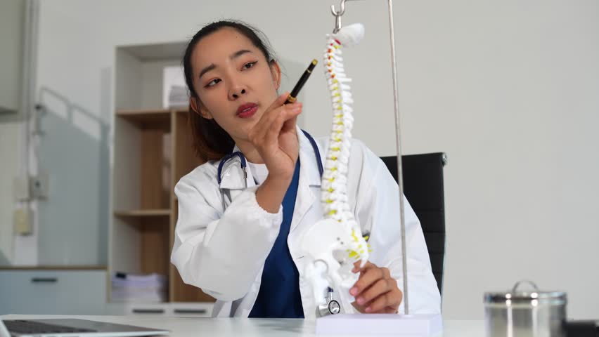 Specialist is analyzing a model of a spine showing the steps of a patient suffering spinal replacement surgery.	