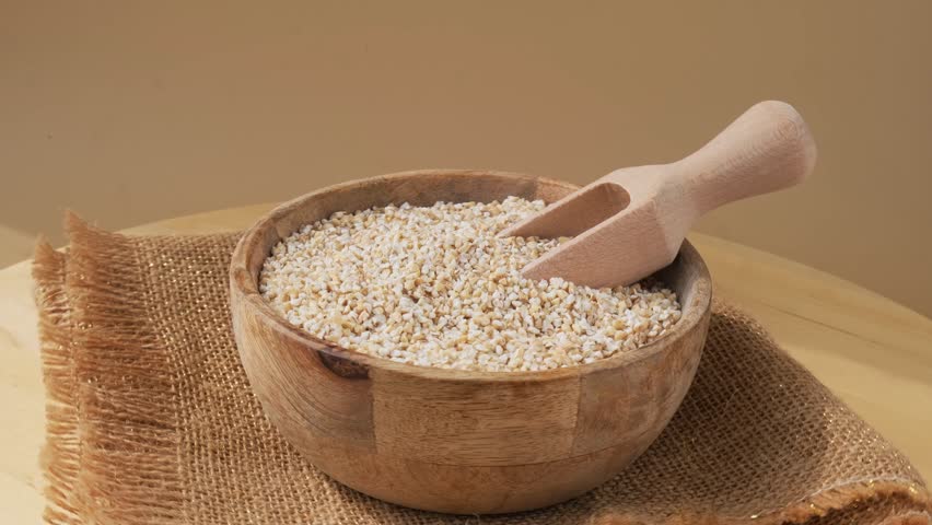 Fine ground barley in neutral beige background. Whole spelt grain species. High protein fiber-rich vegan plant based food ingredient. Gluten free superfood healthy nutritional dietary alternative