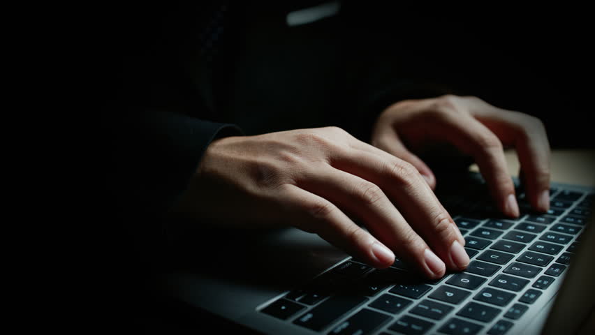 Laptop with hands typing amid glowing cyber attack alerts and red binary code, symbolizing hacking, data breach, and cybersecurity threats