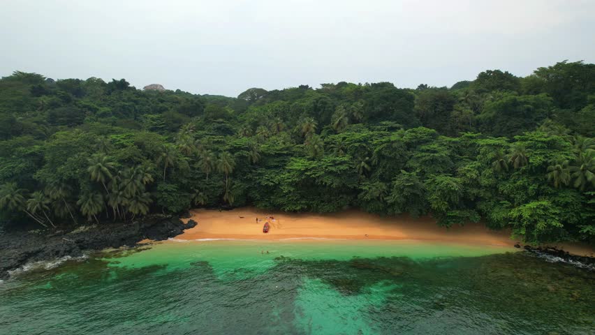 Aerial circular view of the Margarida beach with a boat anchored in the sand along with tourists at ilha do Principe (Prince Island) Sao Tome,Africa