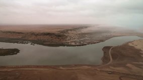 Aerial view of a river estuary where the desert meets the ocean, with nomadic camps and a vehicle visible along the shore near Tan-Tan, Morocco - Powered by Shutterstock - Get 15% off with code: PIKWIZARD15