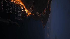 Calheta's lights creating a magical atmosphere at dusk, overlooking the vast Atlantic Ocean in Madeira, Portugal. Aerial, Vertical Video - Powered by Shutterstock - Get 15% off with code: PIKWIZARD15