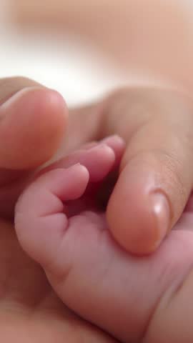 Close up baby hand holding finger mom in a room with a lot of sunlight. The newborn sleeping on the mother