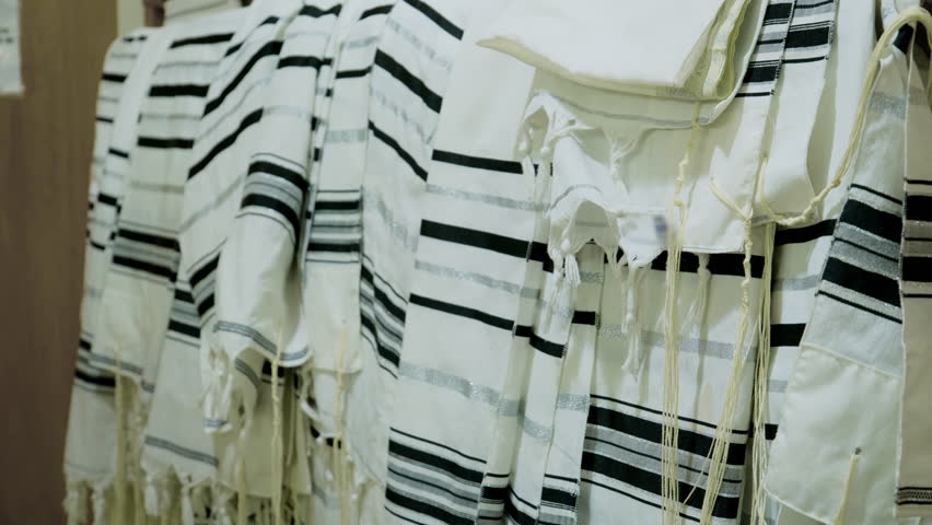 The tallit Jewish prayer shawls hanging neatly, in a synagogue or place of worship. The tallitot with knotted fringes tzitzit.