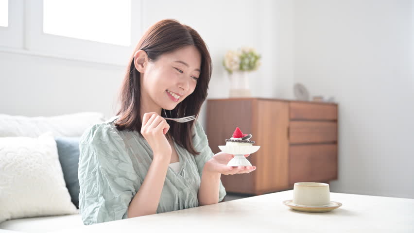 A Japanese woman smiling happily as she eats sweet treats. Sweets are a separate stomach. Close-up.