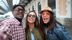 Diverse group of cheerful friends capturing pre departure memories, smiling and taking group selfie at bustling train station platform before embarking on shared adventure - Powered by Shutterstock - Get 15% off with code: PIKWIZARD15