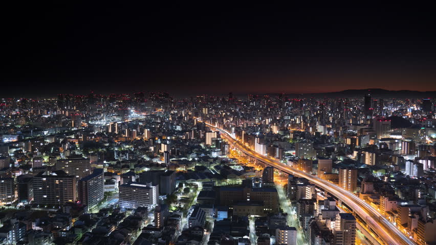 osaka city slyline aerial shot time lapse from night to day,high view of metropolis cityscape at sunrise