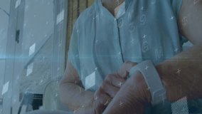 Senior woman raising arm and adjusting wrist health tracker, viewing animated health graphs. Gerontology, technology, wellness, digital, lifestyle, innovation, observational - Powered by Shutterstock - Get 15% off with code: PIKWIZARD15