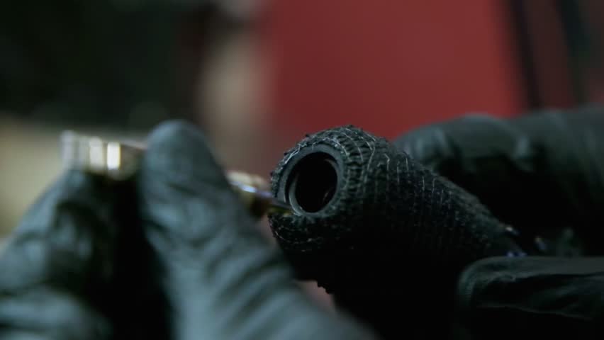 Close up of Tattoo needle being plugged into tattoo gun in slow motion. Turned on and starts spitting white ink.