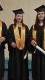 Vertical shot of intercultural zoomers in academic wear throwing hats up in university hall after commencement - Powered by Shutterstock - Get 15% off with code: PIKWIZARD15