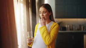 Sad pregnant woman taking supplement with water, feeling unwell, seeking relief - Powered by Shutterstock - Get 15% off with code: PIKWIZARD15