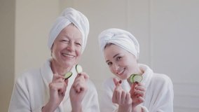 Portrait of senior woman and daughter in bathrobes posing with cucumber slices - Powered by Shutterstock - Get 15% off with code: PIKWIZARD15