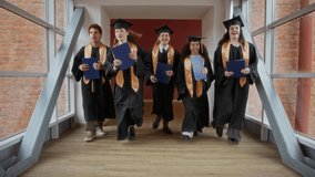 Low angle tracking shot of multiethnic bachelors with diplomas running along corridor of university after ceremony - Powered by Shutterstock - Get 15% off with code: PIKWIZARD15