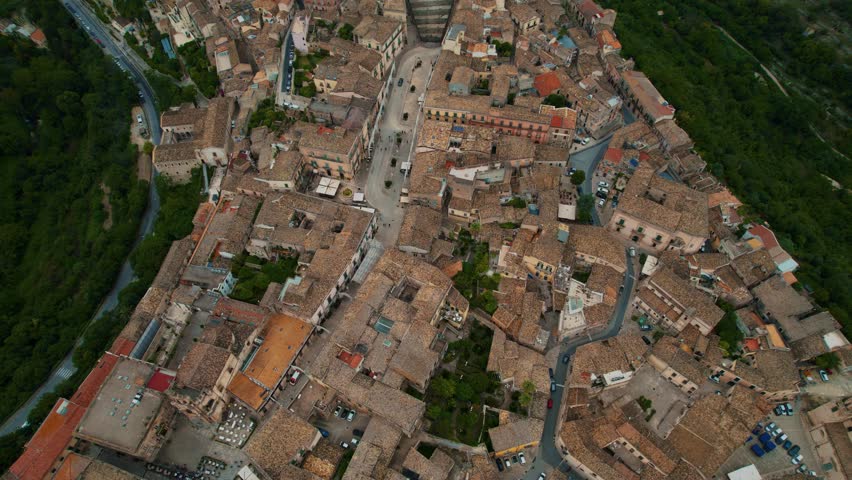 Ragusa Ibla old town with layered tiled rooftops, Baroque cathedral. Scenic aerial, bright daylight