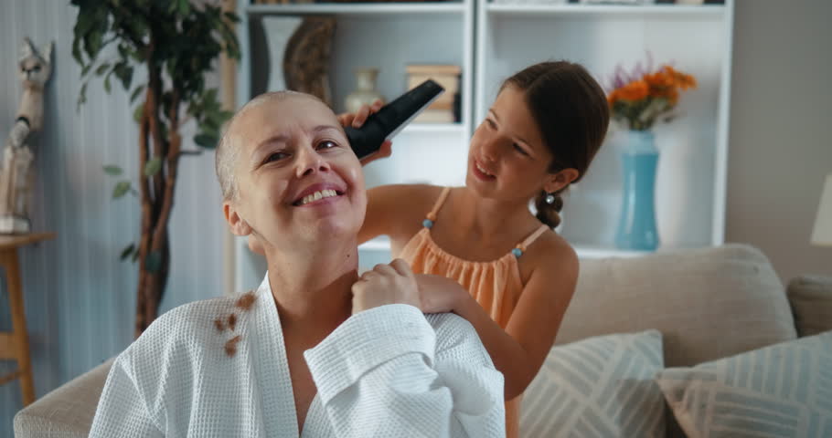 Daughter provides emotional support with a hug to her mother cancer survivor and who cut her hair short due to chemotherapy.