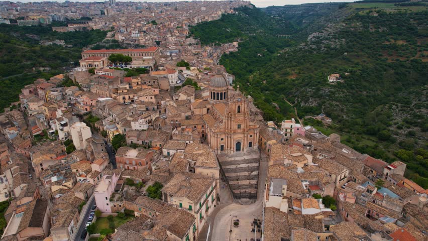 Top-down aerial view of Ragusa Ibla rooftops and curved roads in cinematic daylight. Sicily, Italy.