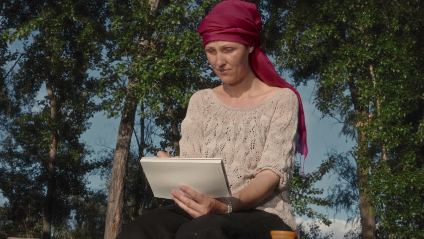 Female artist painting river landscape with watercolor while sitting on the river bank