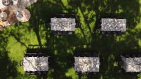 An aerial view shows elegantly arranged tables set for outdoor wedding dining in a charming, lush garden setting. - Powered by Shutterstock - Get 15% off with code: PIKWIZARD15