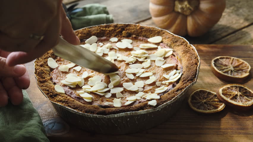  Cutting Pumpkin Pie Sprinkled with Almonds. Homemade cooking thanksgiving pie