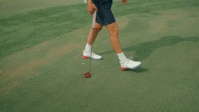 Slow-motion clip showing a male golfer from the waist down walking across the putting green with a red putter, to read the green. Capturing calm preparation, rhythm, and detail ahead of a putt. - Powered by Shutterstock - Get 15% off with code: PIKWIZARD15