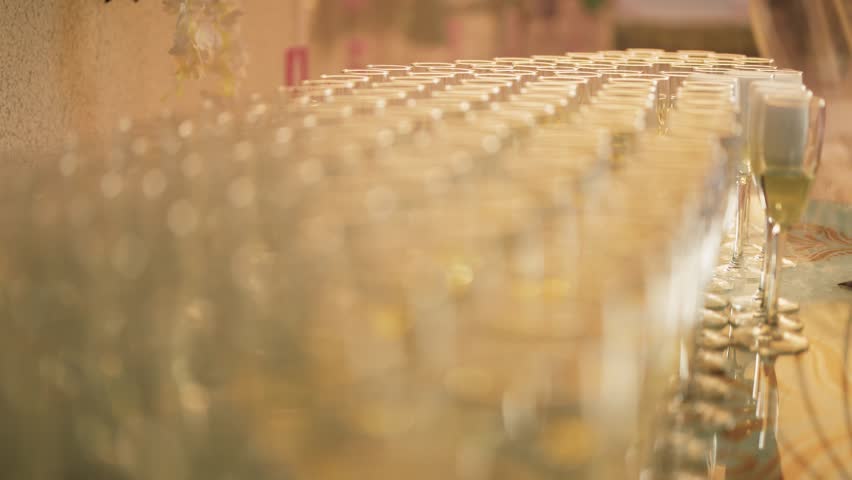 Overhead view of champagne glasses rims glistening under the golden light of the setting sun. Close up focus pull shot.