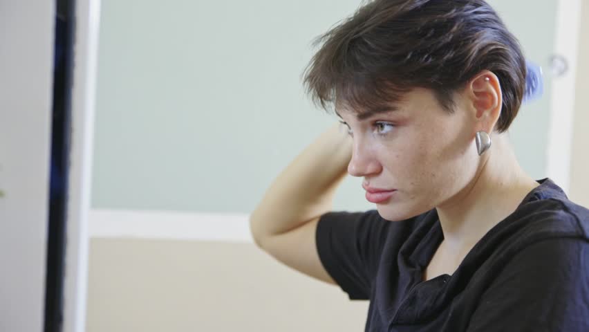 Woman combing hair in front of mirror