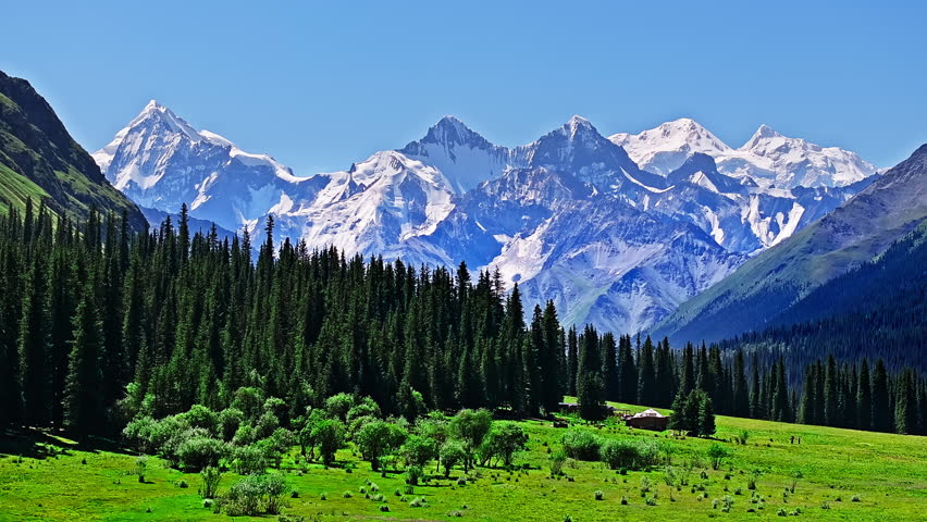 Aerial shot of majestic snow mountain range and green valley natural landscape in Xinjiang, China.