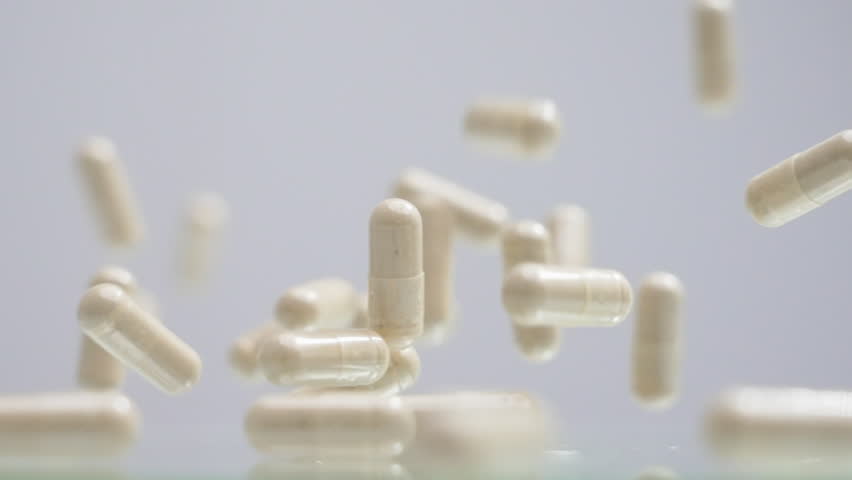 Capsules pills medicine supplements falling down and bouncing in slow motion shot with dynamic bounce and clear focus showing smooth movement around health product video