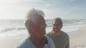 Senior couple walking on beach with smartphone causing social media hearts and thumbs-up drifting. Senior, beach, friendship, connection, relaxation, happiness, lifestyle - Powered by Shutterstock - Get 15% off with code: PIKWIZARD15