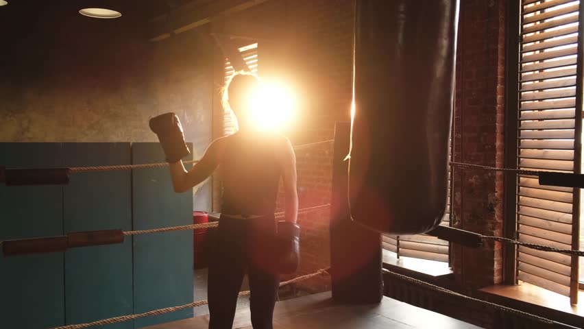 Woman fighter with boxing gloves standing on boxing ring celebrating victory. Woman boxing champion showing raising hands up. Strong powerful girl on boxing ring arena. Competition champion winner
