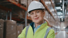 Portrait of charming warehouse supervisor wearing protective helmet smiling gently while standing near storage racks. Leading daily tasks or guiding colleagues through inventory procedures. - Powered by Shutterstock - Get 15% off with code: PIKWIZARD15