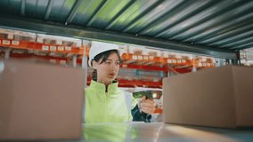 Close view of female warehouse worker in high-visibility jacket and hard hat using tablet and barcode scanner between shelves. Focused looking while checking inventory data in cardboard boxes. - Powered by Shutterstock - Get 15% off with code: PIKWIZARD15