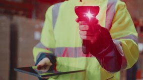 Warehouse employee in reflective safety jacket holding barcode scanner with red laser beam and using digital tablet, performing inventory check or package tracking in industrial storage area. - Powered by Shutterstock - Get 15% off with code: PIKWIZARD15