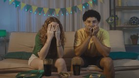 Multiracial couple reacts with frustration after a missed goal during a match at home. Wearing Brazil colors, they express disappointment and tension in a realistic fan moment.
 - Powered by Shutterstock - Get 15% off with code: PIKWIZARD15