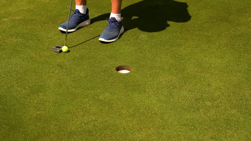 Golfer puts ball at short distance with precision on the green. Calm, focused movement for accurate shot. Close-up of putter, ball, and smooth stroke. Ideal for sports, technique, or ads.