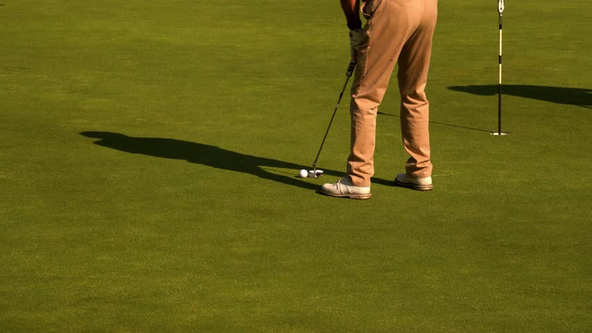 Golfer puts ball at short distance with precision on the green. Calm, focused movement for accurate shot. Close-up of putter, ball, and smooth stroke. Ideal for sports, technique, or ads.