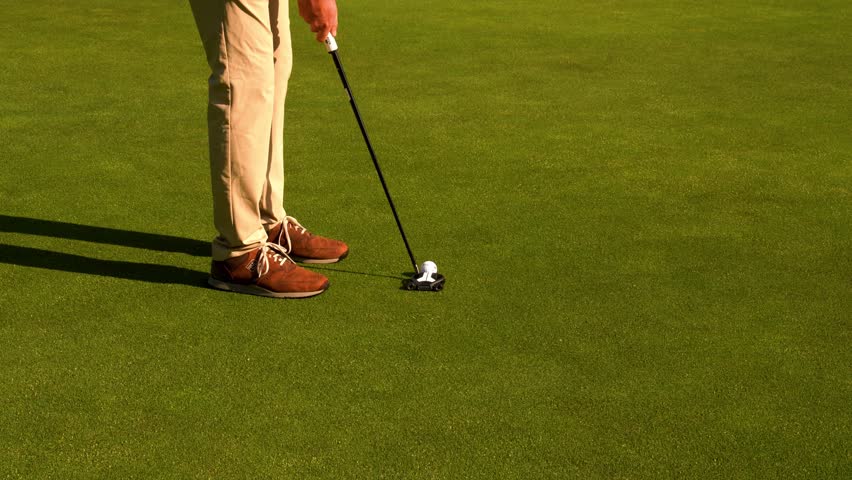 Golfer puts ball at short distance with precision on the green. Calm, focused movement for accurate shot. Close-up of putter, ball, and smooth stroke. Ideal for sports, technique, or ads.