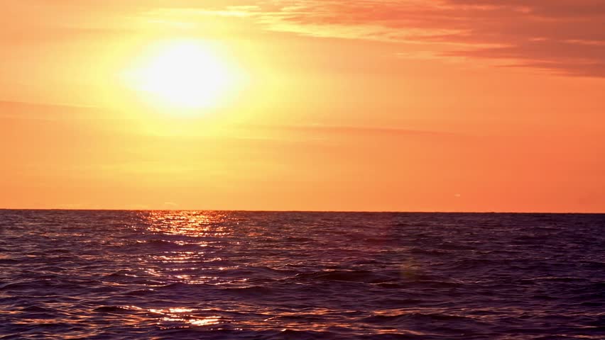 Silhouette of people riding jet skis at sunset far from the shore.