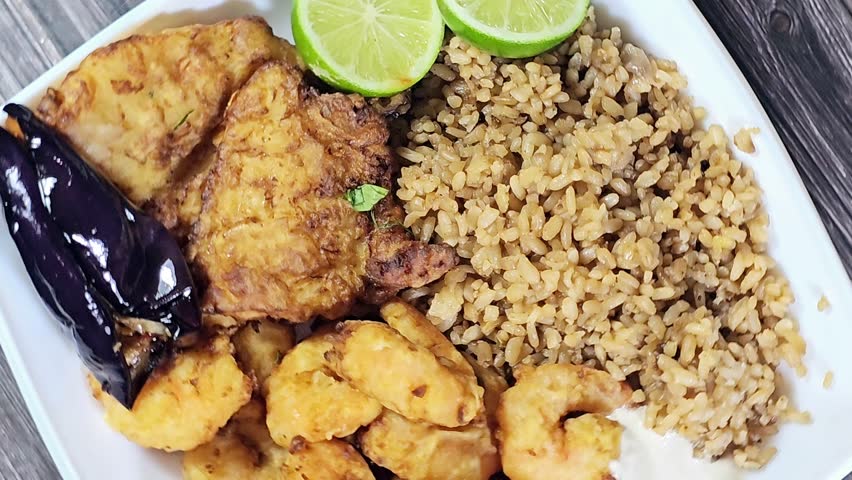 A plate of seafood of Fried Epinephelus fish fillet, Egyptian fish rice and Fried shrimps covered with flour and fried in deep oil, lemon and Pickled roast fried Aubergine eggplant