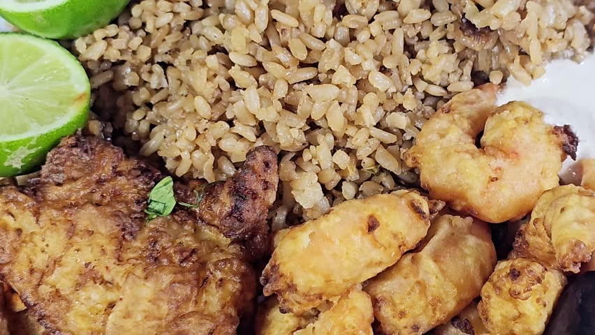 A plate of seafood of Fried Epinephelus fish fillet, Egyptian fish rice and Fried shrimps covered with flour and fried in deep oil, lemon and Pickled roast fried Aubergine eggplant