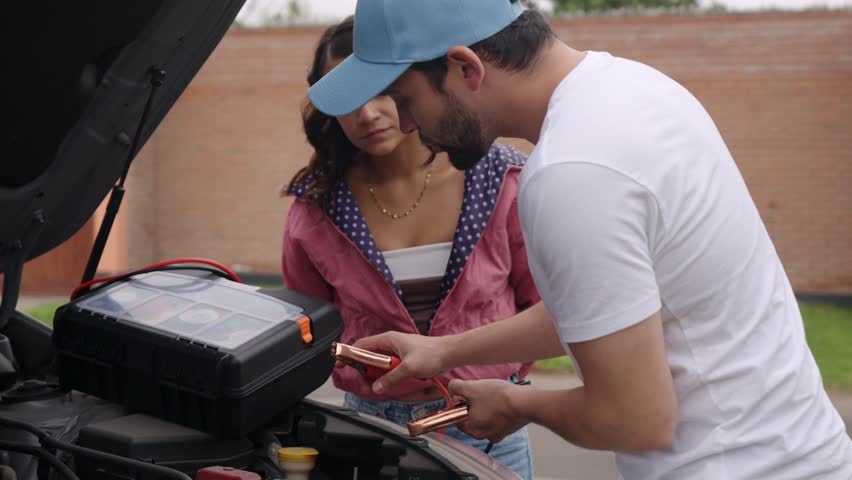 Collaborative road trip problem solving with couple jumpstarting vehicle battery, working together to overcome unexpected automotive challenge during summer travels