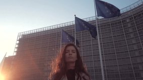Confident woman at EU Commission HQ, sunset behind fluttering flags. - Powered by Shutterstock - Get 15% off with code: PIKWIZARD15