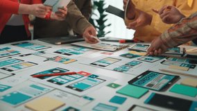 A diverse team collaborates on user experience design within a modern workspace, actively discussing ideas while using digital devices and prototypes on a table. SACTR - Powered by Shutterstock - Get 15% off with code: PIKWIZARD15